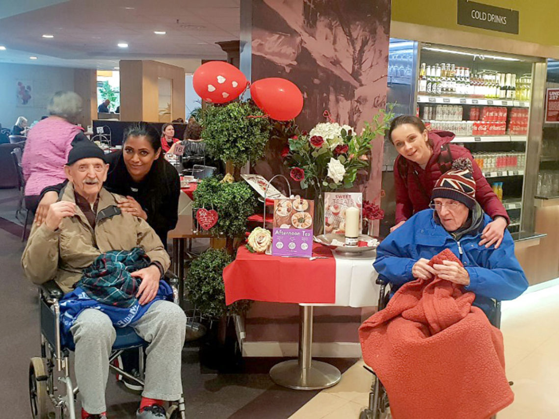Residents and staff of Lukestone Are Home standing next to a valentine display at Dobbies Garden Centre