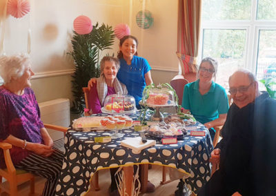Staff and residents around a table of cupcakes at Lukestone Care Home