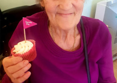 Female resident smiling at the camera, holding a cupcake