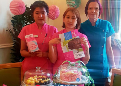 Staff standing by a table of cupcakes, showing the charity leaflets