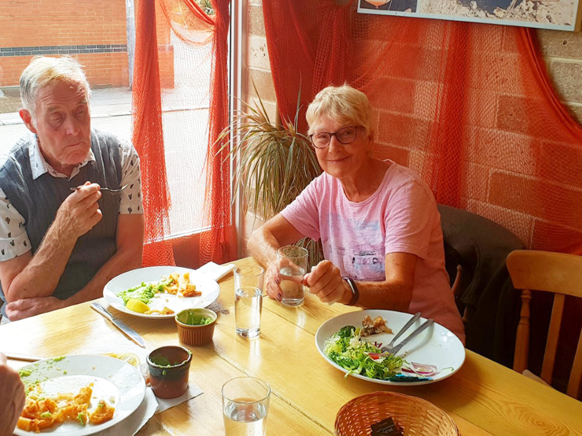 Residents at a table enjoying lunch during an outing to Folkestone