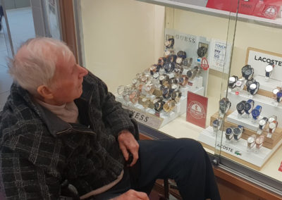 Lukestone Care Home male resident admiring the watches in a shop window at a shopping centre