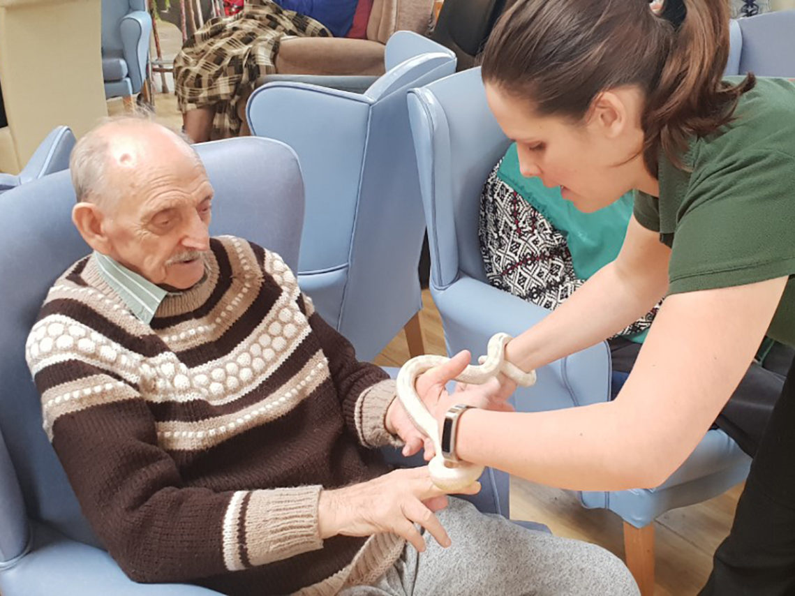 Lukestone Care Home resident and member of staff from Wild Science holding a snake
