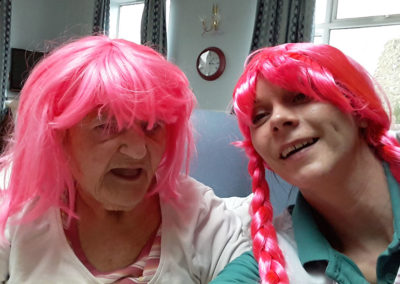 Resident and staff member wearing bright pink wigs at Lukestone Care Home